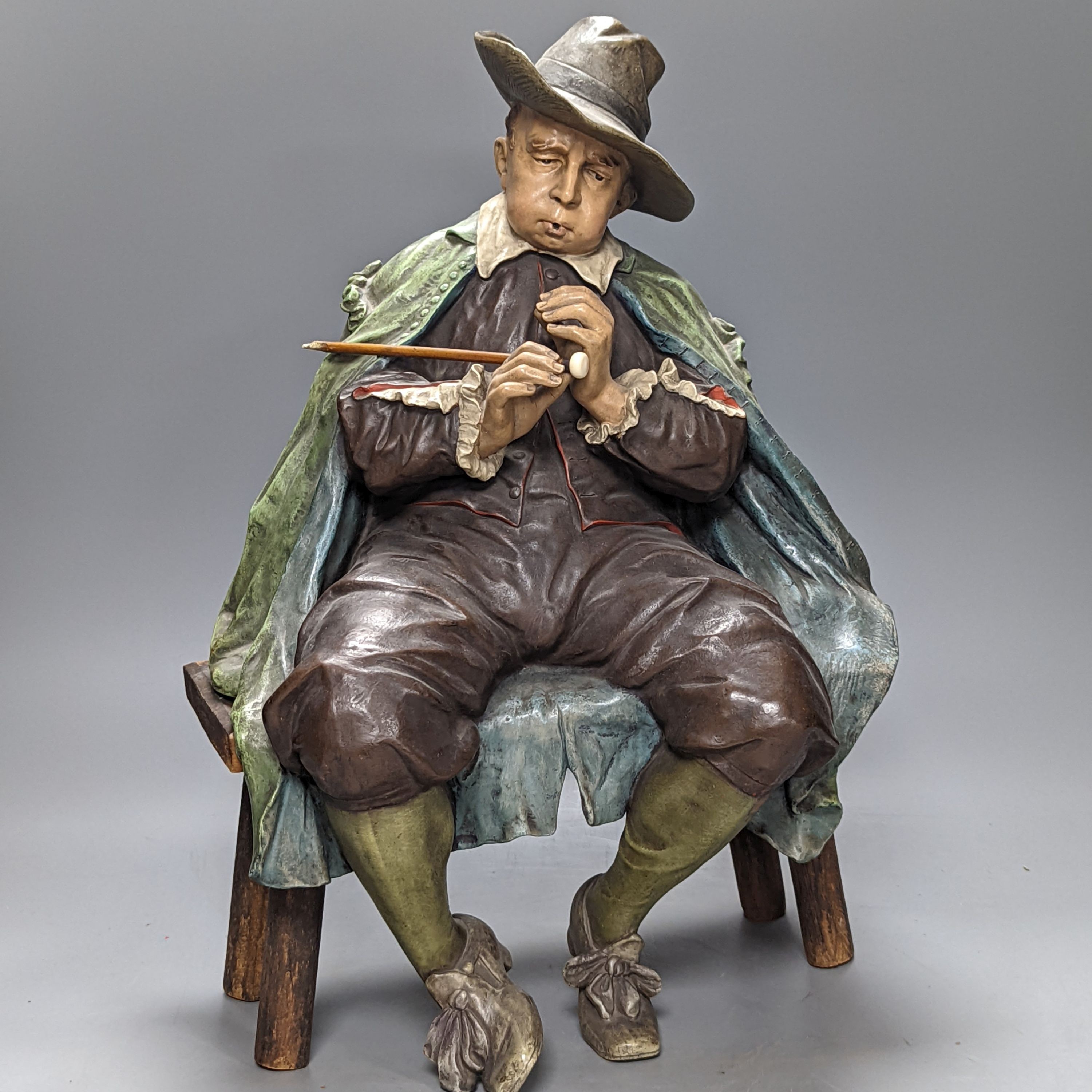 A pair of late 19th/early 20th century Austrian cold painted terracotta figures of musicians in 17th century dress, seated on wood stools 46cm